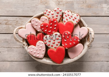 Basket with tasty heart shaped cookies on grey wooden background. Valentine's Day celebration Royalty-Free Stock Photo #2410517077