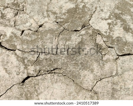 The stone wall of an old building with crumbling plaster and many winding, deep cracks. Copy space. Selective focus. Royalty-Free Stock Photo #2410517389