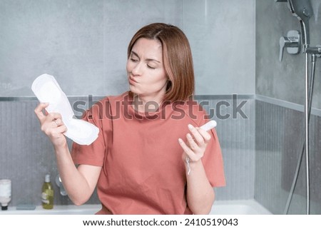In a thoughtful moment, a woman contemplates her choice between pads and tampons, considering the comfort and convenience of each option Royalty-Free Stock Photo #2410519043