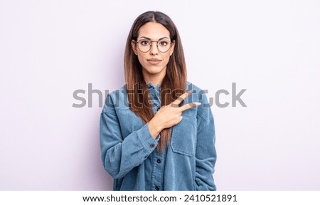 pretty hispanic woman feeling happy, positive and successful, with hand making v shape over chest, showing victory or peace