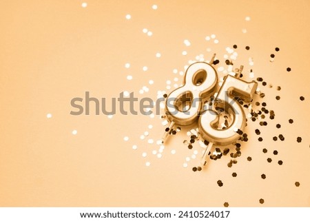 85 years celebration festive background made with golden candles in the form of number Eighty-five lying on sparkles. Universal holiday banner with copy space. Royalty-Free Stock Photo #2410524017