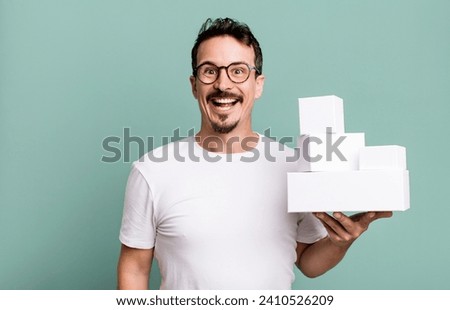 adult man looking happy and pleasantly surprised. blank boxes packaging concept