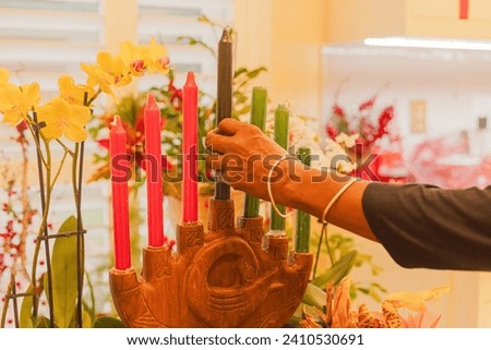A black hand holding the black candle which represents the people.