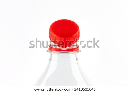 Red tethered cap on bevarage bottle. Mandatory attached cap in european union. Ensuring that bottles are recycled together with their caps and that loose caps no longer end up in the environment. Royalty-Free Stock Photo #2410535845