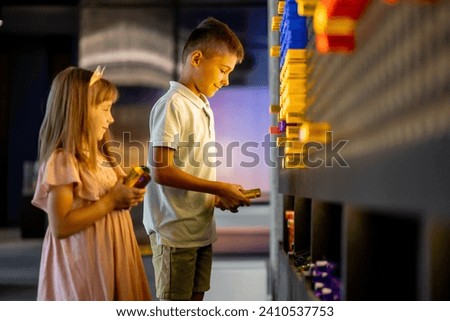 Kids making a picture with colored chips on the wall, playing on interactive models in science museum. Concept of children's entertainment and learning Royalty-Free Stock Photo #2410537753