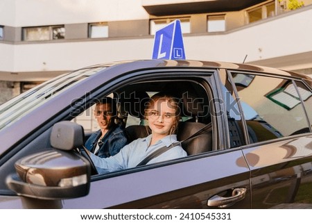 A young female student driver with her driving instructor. Driving school and people concept. Brown car with blue L plate on a roof.