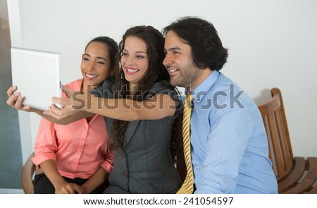 Three business executives talking a picture with a tablet