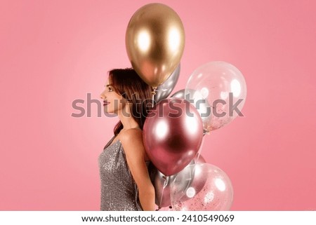 A serene woman in a sparkling silver dress gazes into the distance, her profile accentuated by a bunch of elegant metallic balloons on a warm pink background. Holiday celebration event