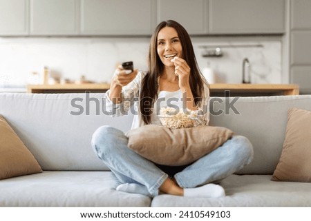 Happy Beautiful Young Woman Holding Remote Controller And Eating Popcorn At Home, Cheerful Millennial Female Watching TV Show While Relaxing On Couch In Cozy Living Room, Copy Space