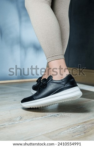 Black women's sneakers. Collection of women's leather shoes. Female legs in leather black casual sneakers. Stylish women's sneakers.