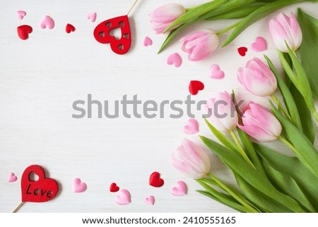 Wooden white background with pink tulips and hearts, copy space for text for the holiday Valentine's Day Royalty-Free Stock Photo #2410555165