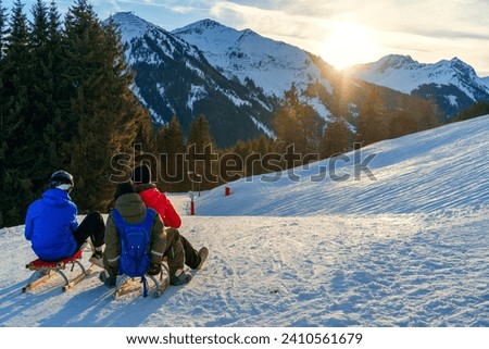 Friends ready for sledding against a sunset backdrop in the Alps, capturing a popular winter holiday activity in nature the mountain's tranquil beauty, a serene moment before an exhilarating descent