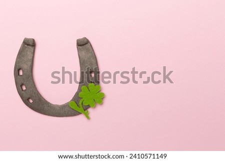 Metal horseshoe with clovers on color background, top view. St. Patricks day concept
