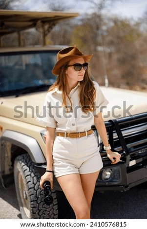 Happy young woman in luxury safari looking for wild animals
