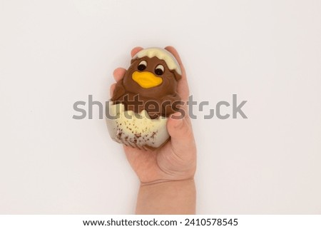 Kid holding figure of chocolate chicken hatched from an egg for Easter