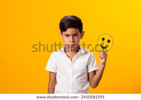 Upset boy holding happy and sad faces on two pieces of memo paper.