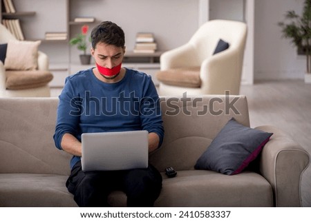 Mouth closed young man working from home Royalty-Free Stock Photo #2410583337