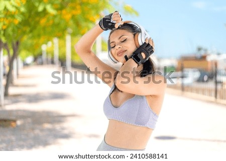 Young pretty sport woman at outdoors listening music and dancing