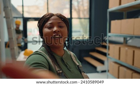 African american warehouse head of logistics using selfie smartphone camera, filming introduction video for new interns starting job in storage facility, teaching them safety measures