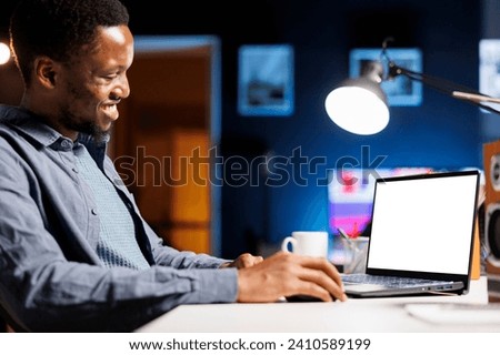 While telecommuting, self employed individual glances at empty layout on laptop and builds his abilities at home. Employee enjoying self education online class package, personal program. Royalty-Free Stock Photo #2410589199