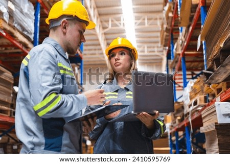 Paper and cardboard factory warehouse workers using a digital tablet while recording inventory. Logistic employees working with business management software in a large storage distribution centre Royalty-Free Stock Photo #2410595769