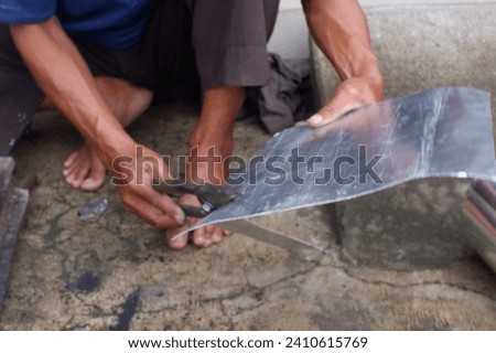 Experts on cooking POTS, Indonesia, January 10, 2023 pan repairman, replaces the bottom of a damaged pan, using the traditional method, done by hand, with good results, rather than buying a new item Royalty-Free Stock Photo #2410615769