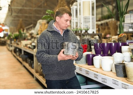 Male seller is standing near clay pots in stock. High quality photo
