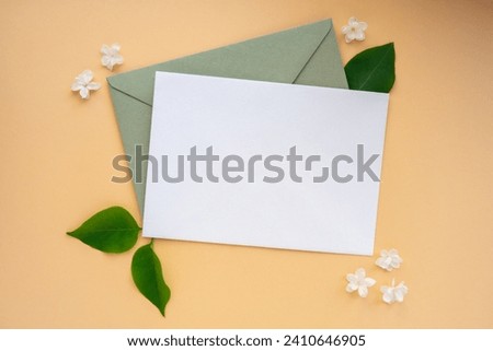 Composition with empty envelope and beautiful spring lilac flowers on beige background. Mockup card invitation greeting card postcard copy space template. Branches of lilac blooming bouquet. 