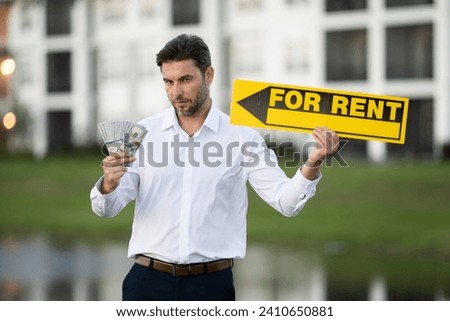 a man in a white shirt holding money in his hands. real state agent giving new house key. Estate agent with customer before contract signature. male real state agent with a for sale or rent sign.