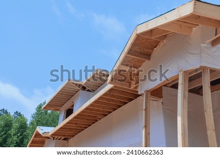 Currently, corner is being constructed with beams for eaves, planks for roof, wooden rafters frame Royalty-Free Stock Photo #2410662363