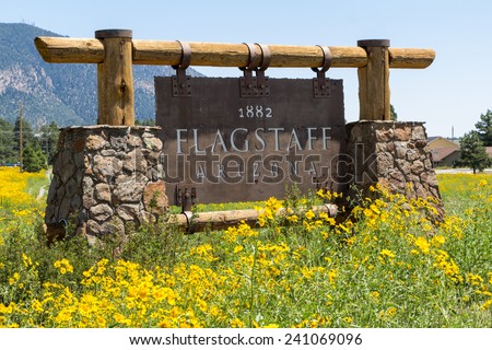 Entering sign Flagstaff in a mountain landscape with yellow flowers Royalty-Free Stock Photo #241069096
