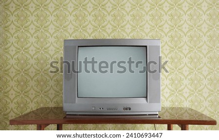 Old TV on the nightstand against the background of wallpaper. Royalty-Free Stock Photo #2410693447