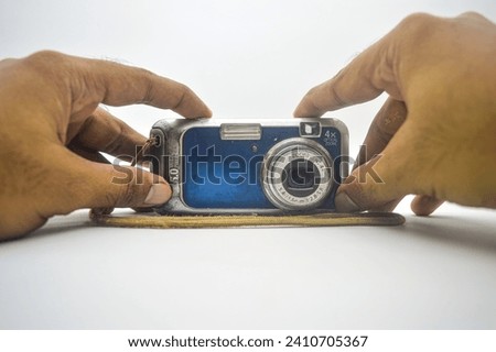 hand holding an old school pocket camera like a selfie isolated on white background