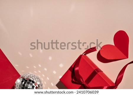 Festive Valentine day celebration template for business branding, red paper heart, gift box, mirror ball on pastel pink background with reflections and shadows in bright light.