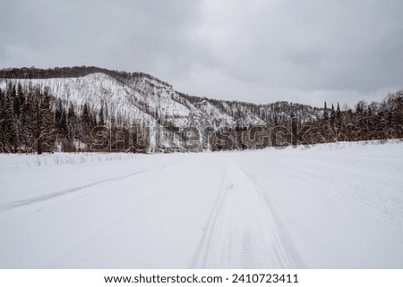 Beautiful winter landscape in cloudy weather, snowmobile tracks in the snow, solo trip to the northern regions of the country, cold winter. High quality photo