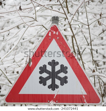 winter warning sign shows danger of ice and snow at street 