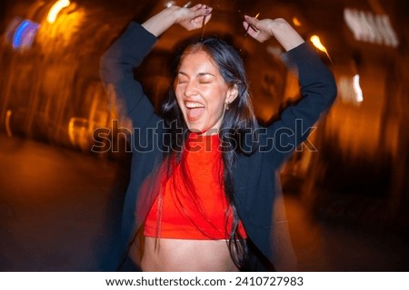Night photo with flash and motion of an excited woman dancing alone in the city street