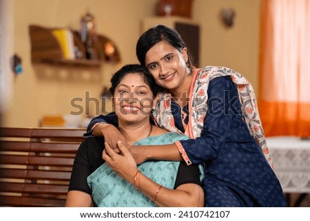 happy smiling Mother with daughter looking at camera by embracing or hugging each other at home - concept of family support, companion and emotional bonding. Royalty-Free Stock Photo #2410742107