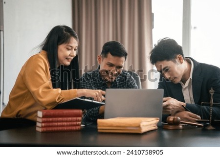 Asian legal team in meeting. woman and two men discussing over documents with law books and gavel on the table, indicating legal setting.