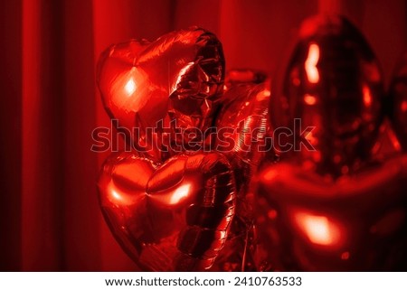 Extravagant glamour background with red foil heart air balloons for love party. Beautiful romantic burlesque room place for st valentines holiday illuminated vanity makeup mirror muffled light Royalty-Free Stock Photo #2410763533