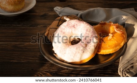 Top view: Delicious soft sugar-glazed donuts eaten with morning coffee and celebrations on a plate on an old plank floor.