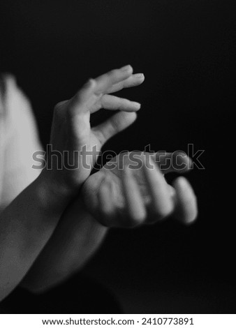 Refined and elegant hands of a dancer, dancing with body parts, black and white portrait of the performer's hands on a dark background Royalty-Free Stock Photo #2410773891