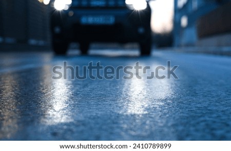 Glazed frost on the asphalt. icy road danger for driving. Close up photo of a road covered with ice after a snowfall and freezing rain. Royalty-Free Stock Photo #2410789899