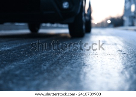 Glazed frost on the asphalt. icy road danger for driving. Close up photo of a road covered with ice after a snowfall and freezing rain. Royalty-Free Stock Photo #2410789903
