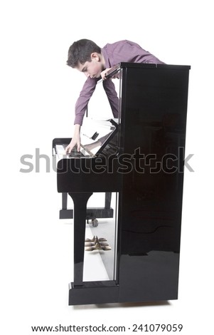 teenage boy and upright black piano in studio with white background