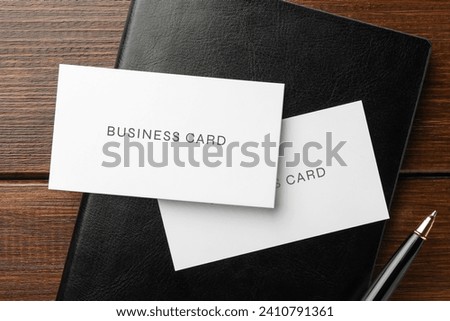 Business cards, pen and notebook on wooden table, top view