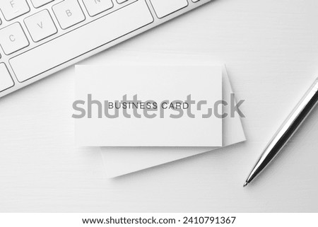 Business cards, pen and computer keyboard on white table, flat lay