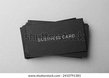 Stack of business cards with text on grey background, top view
