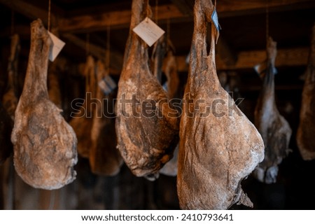 Aging hams hanging in a traditional curing room Royalty-Free Stock Photo #2410793641