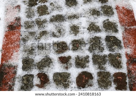 A cobblestone surface with snow and ice